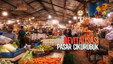 Foto aktivitas pedagang dan pembeli di Pasar Cikurubuk dengan latar bangunan kios tradisional, simbol ekonomi kerakyatan.