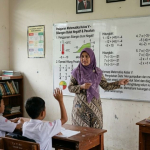 Guru honorer sedang mengajar di ruang kelas sekolah negeri usai muncul isu penghapusan status honorer tahun 2027.
