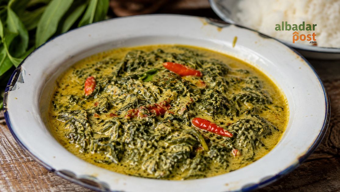 Semangkuk gulai daun singkong santan kental dengan cabai merah dan aroma rempah khas masakan Nusantara.