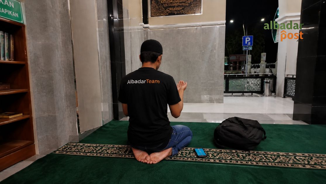 Ilustrasi seseorang sedang berdoa khusyuk di malam hari setelah salat tahajud dengan suasana tenang dan cahaya lampu redup.