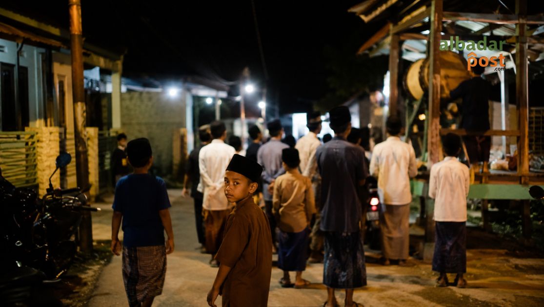 Suasana malam takbiran Dzulhijjah di kampung Indonesia dengan gema takbir, bedug musala, dan warga bersiap menyambut Idul Adha.