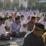 Ilustrasi jamaah mendengarkan khutbah Idul Adha di lapangan masjid dengan suasana pagi penuh takbir.