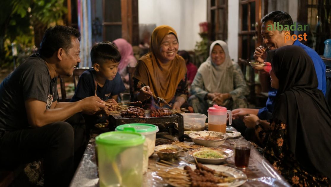 Ilustrasi suasana bahagia makan sate bersama keluarga dan tetangga di Hari Tasyrik.