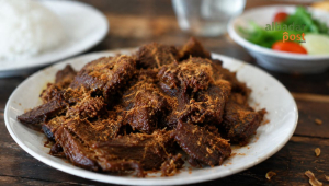 Gepuk daging sapi sisa kurban berwarna cokelat keemasan dengan bumbu meresap dan tekstur empuk khas masakan Sunda.